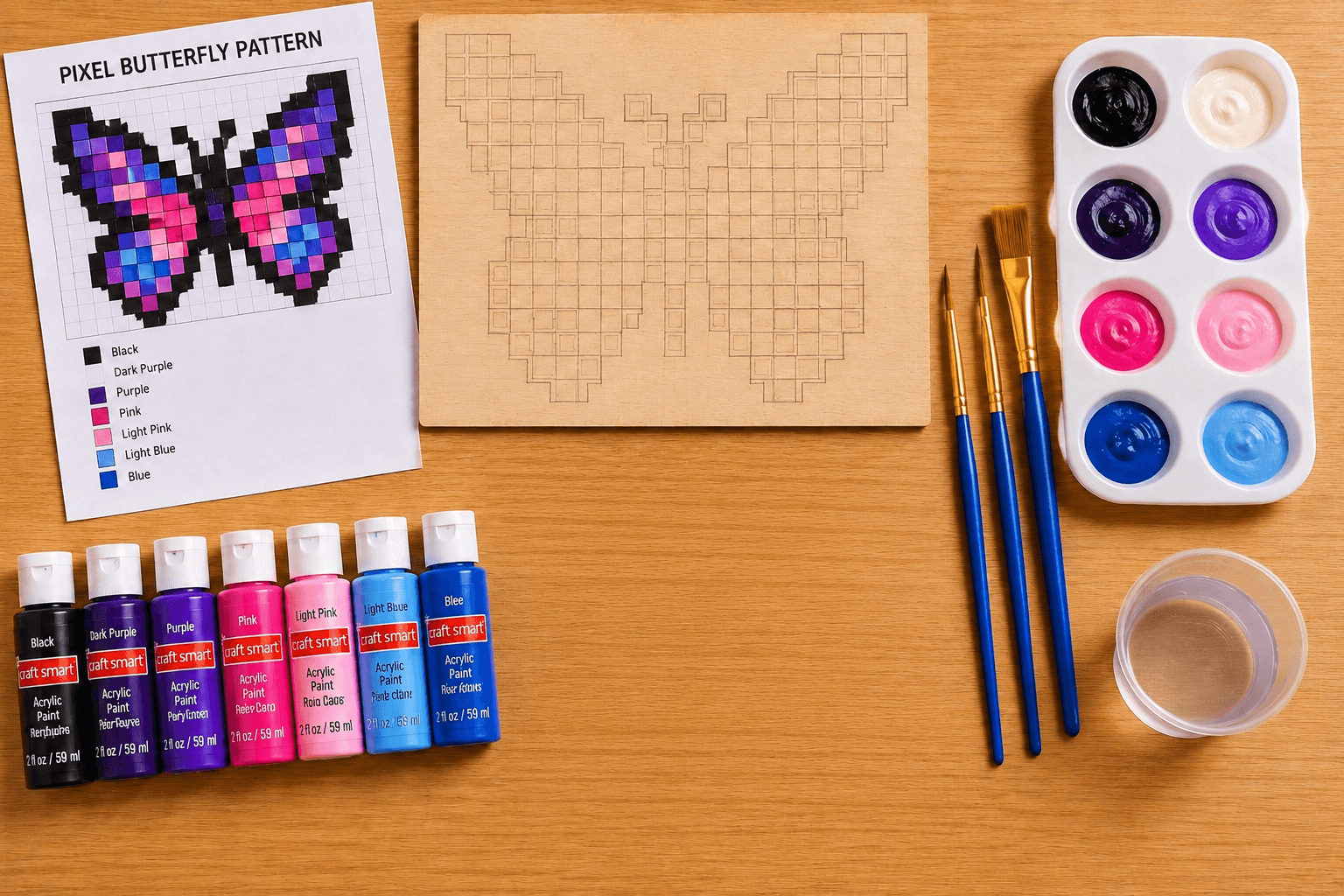 Paint blocks, acrylic paint, brushes, palette, and butterfly pattern arranged on a tabletop